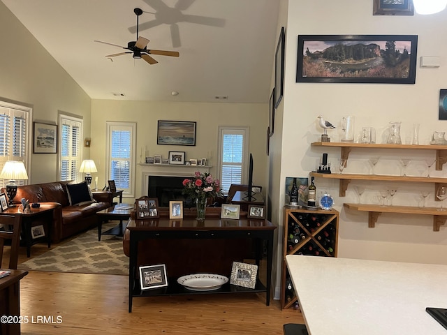 interior space featuring a ceiling fan, lofted ceiling, a fireplace, and wood finished floors