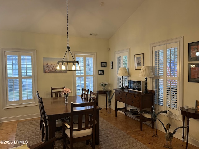 dining space featuring lofted ceiling, baseboards, and wood finished floors