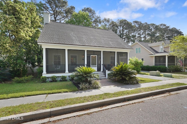 19 Brisbane Dr, Beaufort, SC 29902 - bungalow with roof with shingles, a chimney, a sunroom, and a front lawn