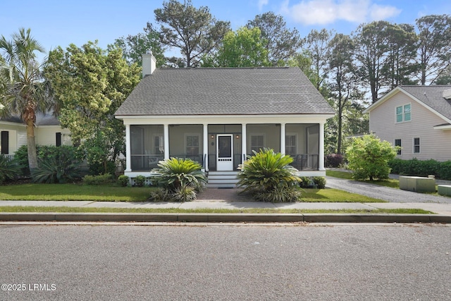 19 Brisbane Dr, Beaufort, SC 29902 - view of front of home featuring a front lawn, a shingled roof, a sunroom, and a chimney