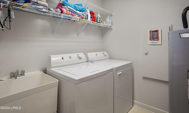 clothes washing area featuring sink, washing machine and dryer, and water heater