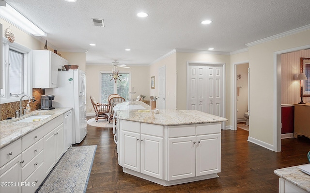 kitchen featuring dark hardwood / wood-style floors, white cabinetry, sink, a center island, and crown molding