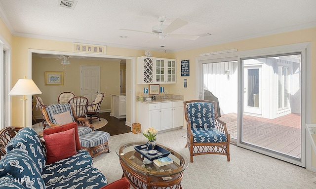 living room with ceiling fan, crown molding, and a textured ceiling