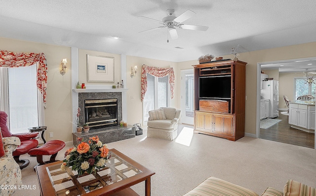 carpeted living room featuring ceiling fan, a premium fireplace, and a textured ceiling