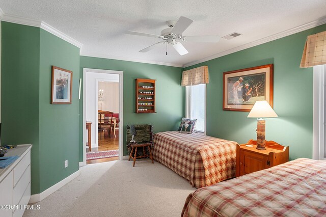 carpeted bedroom with crown molding, ceiling fan, and a textured ceiling