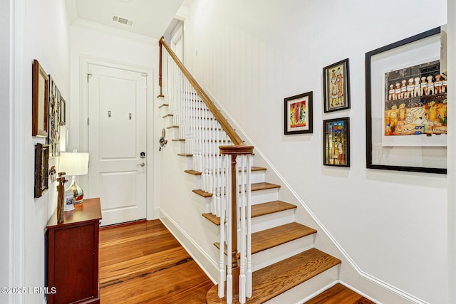 stairs with hardwood / wood-style floors and crown molding