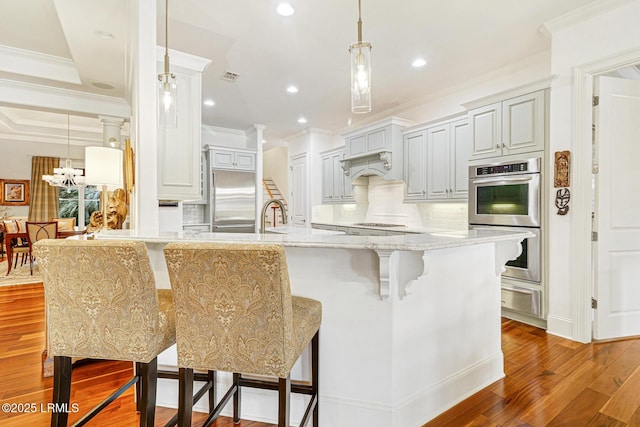 kitchen with a breakfast bar, tasteful backsplash, wood-type flooring, appliances with stainless steel finishes, and gray cabinets