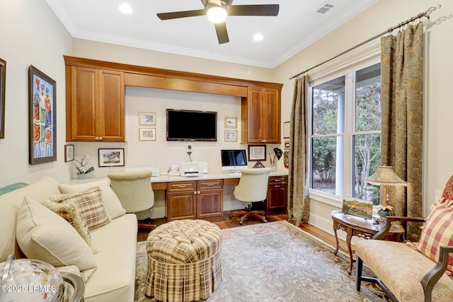 office with wood-type flooring, built in desk, ceiling fan, and crown molding