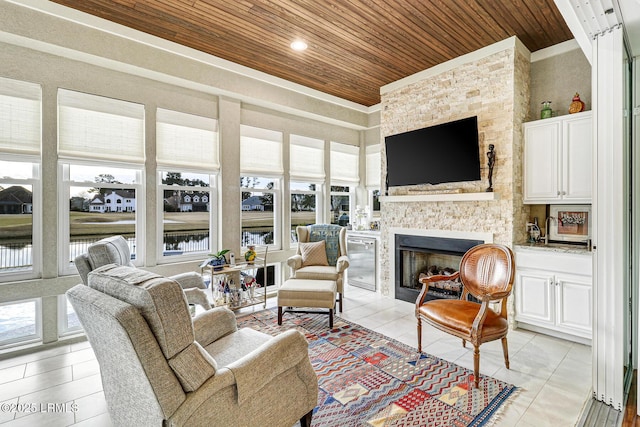 sunroom featuring wood ceiling, a wealth of natural light, and a stone fireplace