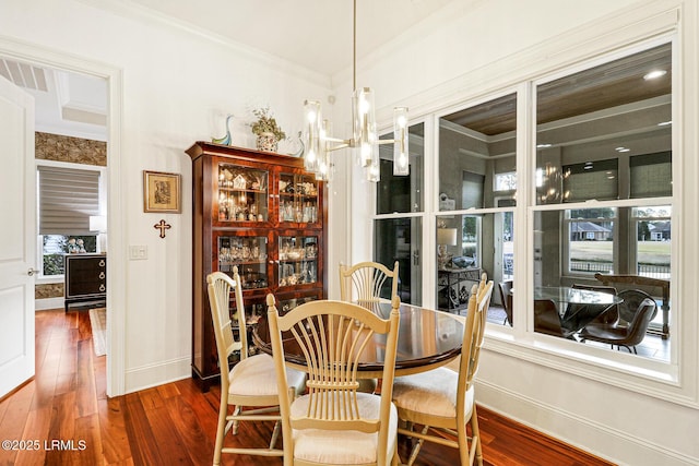 dining space featuring crown molding, a notable chandelier, and dark hardwood / wood-style flooring