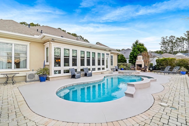 view of swimming pool with exterior fireplace and a patio