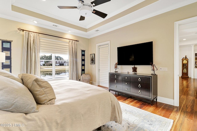 bedroom featuring a raised ceiling, wood-type flooring, crown molding, and ceiling fan