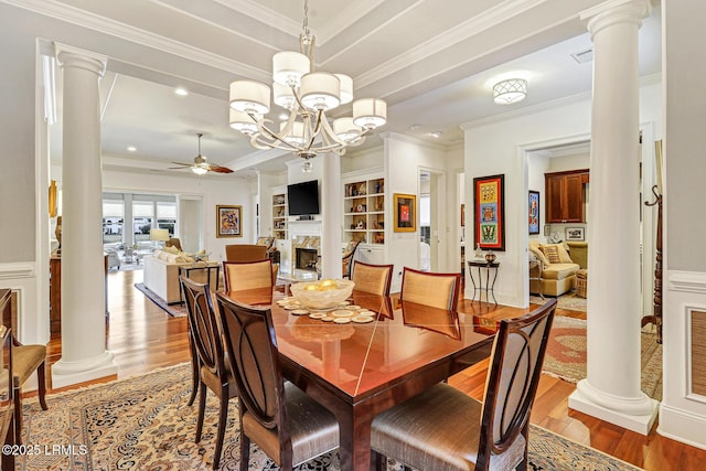 dining room featuring built in shelves, ornamental molding, and decorative columns