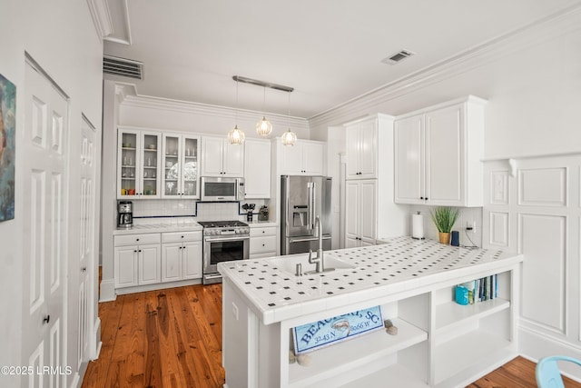 2211 Wilson Dr, Beaufort, SC 29902 - kitchen with appliances with stainless steel finishes, a peninsula, white cabinetry, tasteful backsplash, and glass insert cabinets