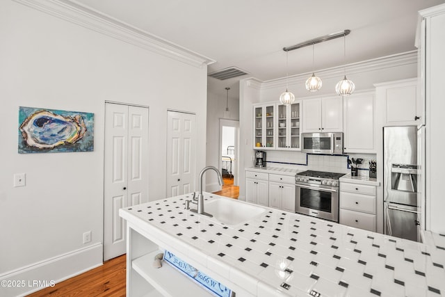 2211 Wilson Dr, Beaufort, SC 29902 - kitchen featuring stainless steel appliances, glass insert cabinets, white cabinetry, wood finished floors, and crown molding