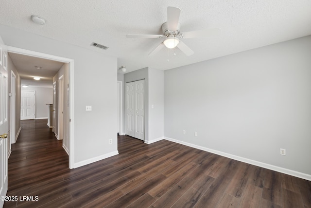 unfurnished bedroom featuring visible vents, baseboards, a textured ceiling, and dark wood-style floors