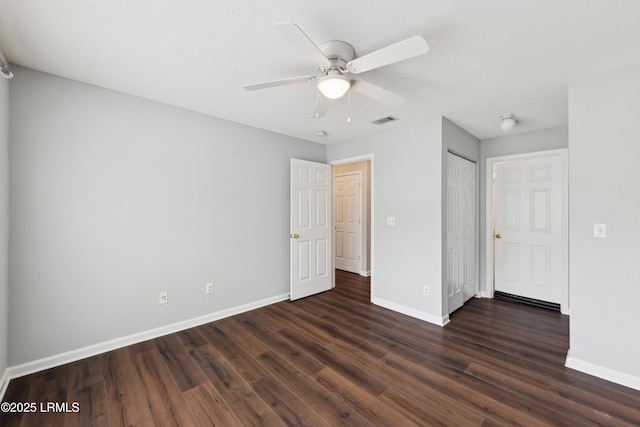 unfurnished bedroom with baseboards, visible vents, ceiling fan, dark wood-type flooring, and a textured ceiling