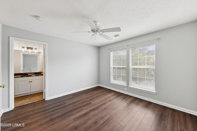 unfurnished bedroom featuring visible vents, a textured ceiling, dark wood-type flooring, and baseboards