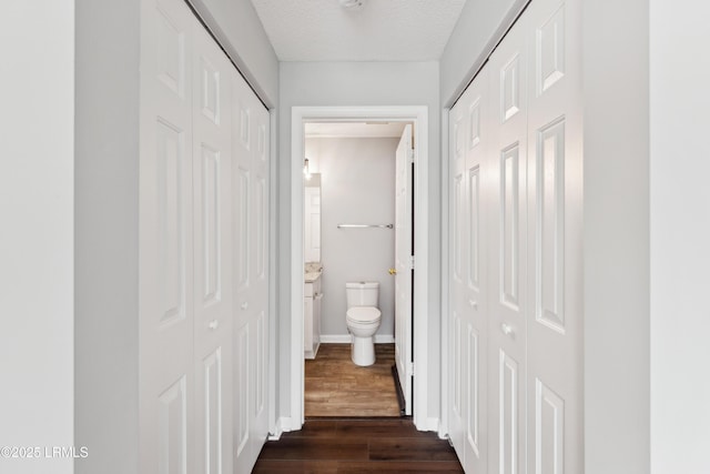 hall with baseboards, dark wood-style flooring, and a textured ceiling