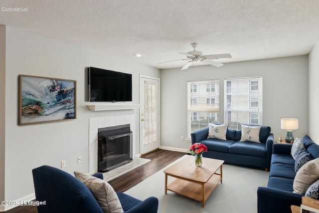 living area featuring baseboards, a textured ceiling, wood finished floors, and a fireplace