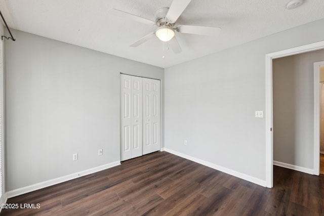 unfurnished bedroom featuring ceiling fan, a closet, baseboards, and dark wood finished floors