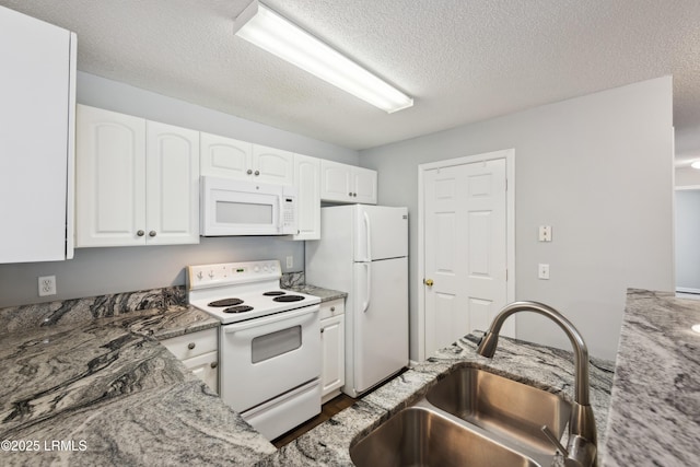 kitchen featuring white cabinets, white appliances, light stone countertops, and a sink