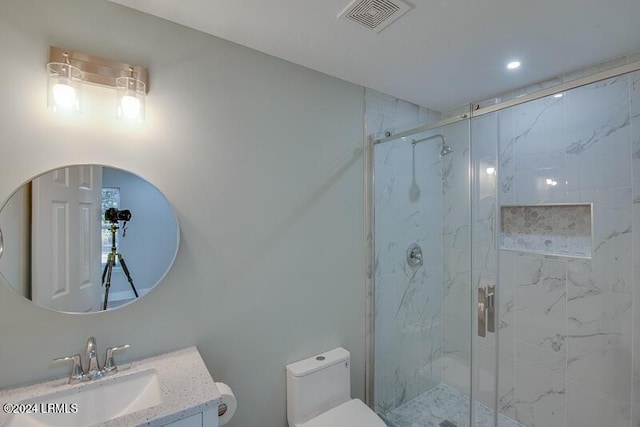 bathroom featuring toilet, vanity, and a shower with shower door