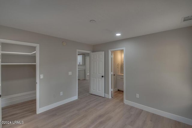 unfurnished bedroom featuring light hardwood / wood-style flooring, a walk in closet, and a closet