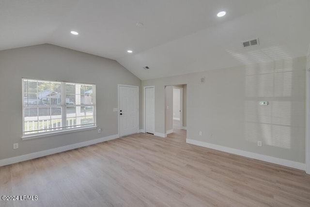 spare room featuring lofted ceiling and light hardwood / wood-style floors