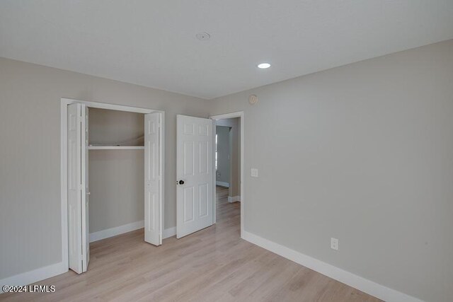 unfurnished bedroom featuring a closet and light wood-type flooring