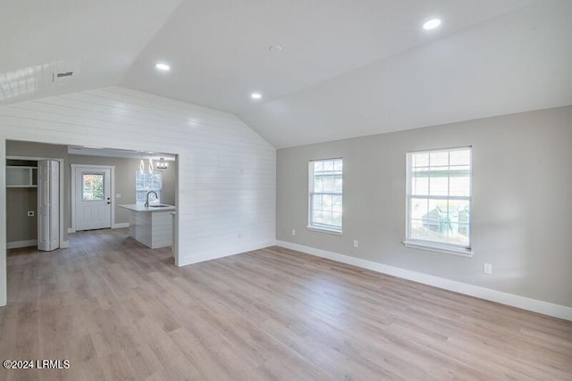 unfurnished living room featuring lofted ceiling, sink, and light hardwood / wood-style flooring