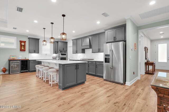 kitchen featuring premium range hood, gray cabinetry, an island with sink, pendant lighting, and stainless steel appliances