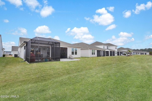 rear view of house featuring a patio, glass enclosure, and a lawn