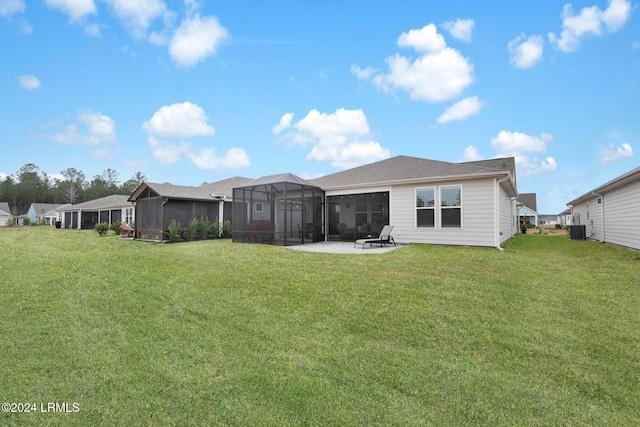 rear view of property featuring a lanai, a patio area, central AC, and a lawn