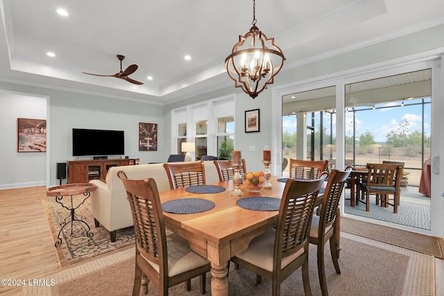 dining space featuring a raised ceiling, ornamental molding, and light hardwood / wood-style floors