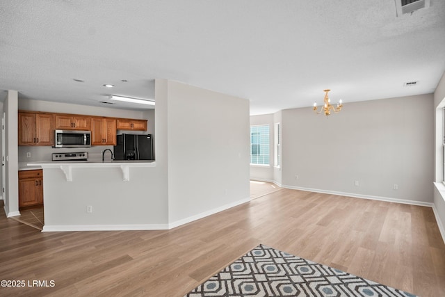 506 Cypress Cv, Bluffton, SC 29910 - kitchen featuring stainless steel microwave, black fridge with ice dispenser, a chandelier, brown cabinets, and light wood finished floors