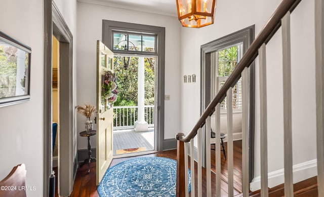 entryway with ornamental molding, dark hardwood / wood-style floors, and a chandelier