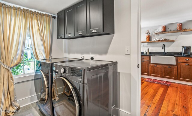 laundry area with cabinets, sink, hardwood / wood-style floors, and washing machine and dryer