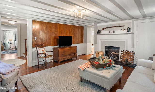 living room with dark hardwood / wood-style floors, wooden walls, and a fireplace