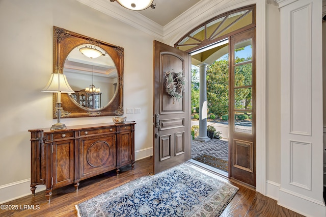 foyer entrance with an inviting chandelier, ornamental molding, dark hardwood / wood-style flooring, and decorative columns