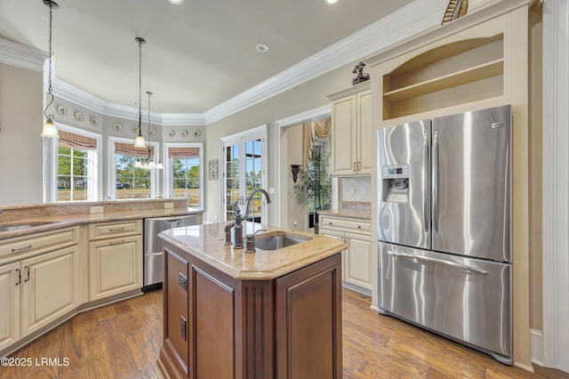 kitchen with sink, decorative light fixtures, a kitchen island with sink, stainless steel appliances, and cream cabinets