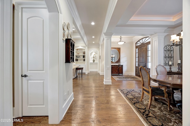 hallway featuring hardwood / wood-style floors, built in shelves, ornamental molding, and ornate columns