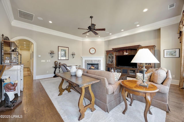 living room featuring ornamental molding, ceiling fan, a fireplace, and light hardwood / wood-style flooring