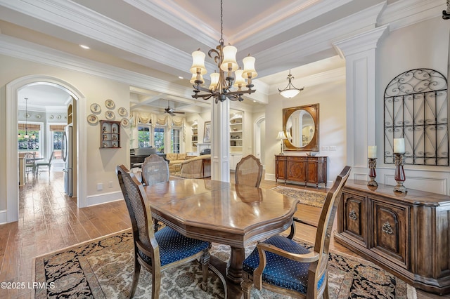 dining area with hardwood / wood-style flooring, crown molding, and ceiling fan with notable chandelier