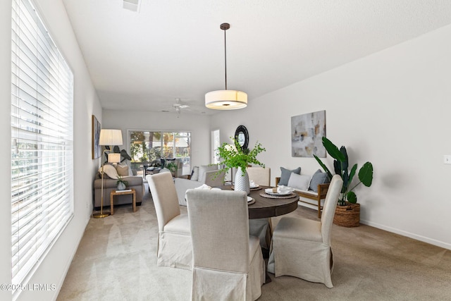 carpeted dining room with ceiling fan