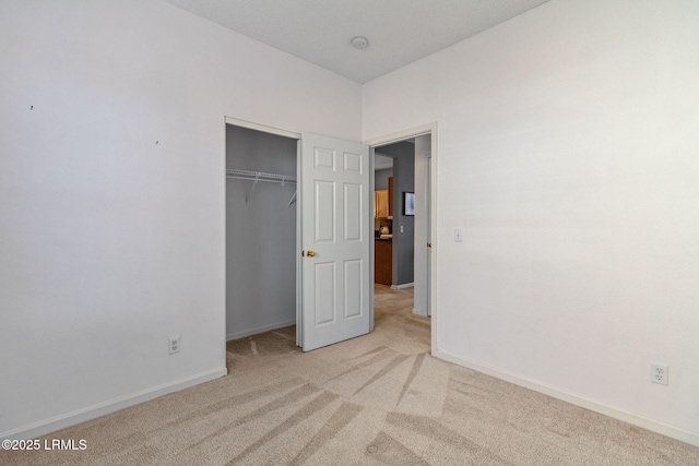 unfurnished bedroom with light colored carpet and a closet