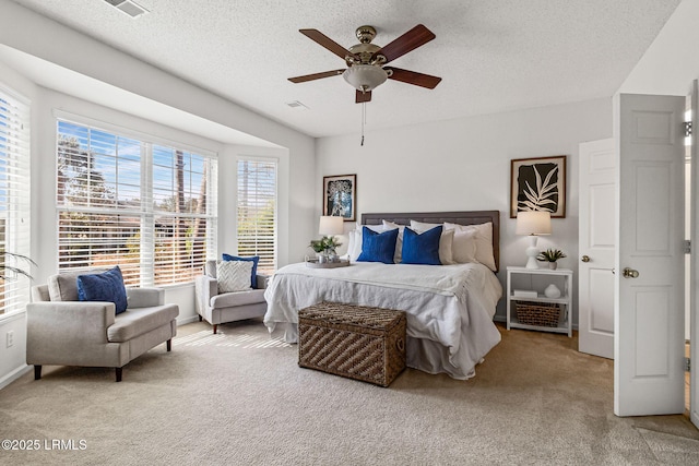 bedroom featuring light carpet, ceiling fan, and a textured ceiling