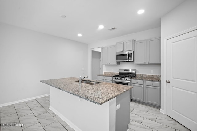 kitchen with sink, gray cabinets, an island with sink, and appliances with stainless steel finishes