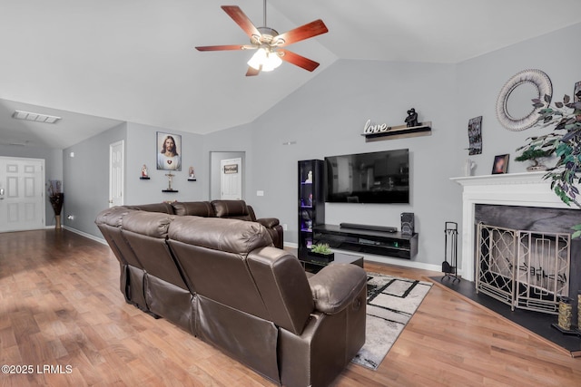 living area featuring lofted ceiling, a premium fireplace, visible vents, and wood finished floors