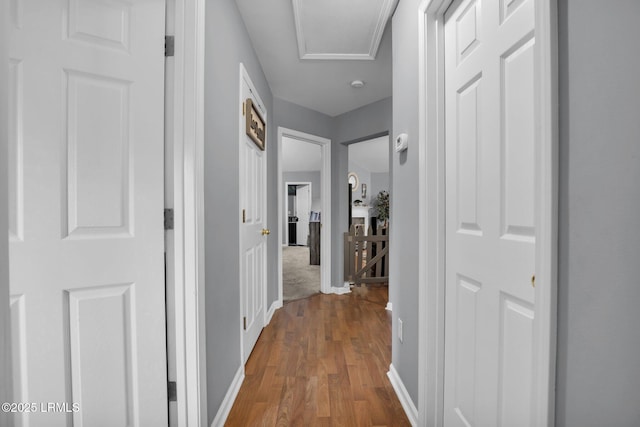 corridor with wood finished floors, attic access, and baseboards